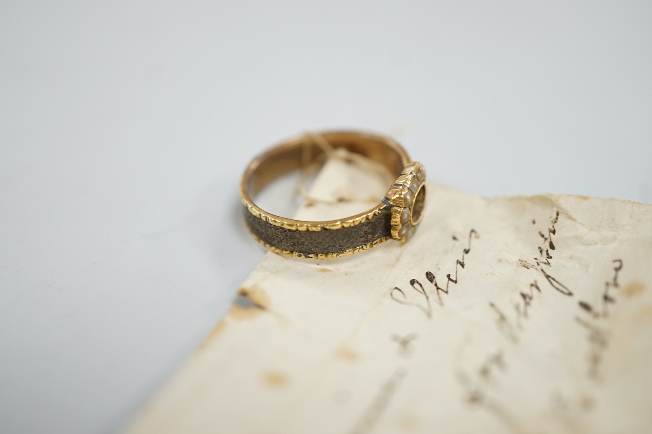 A 19th century yellow metal, split pearl and plaited hair set mourning ring, size O, gross weight 2.9 grams.